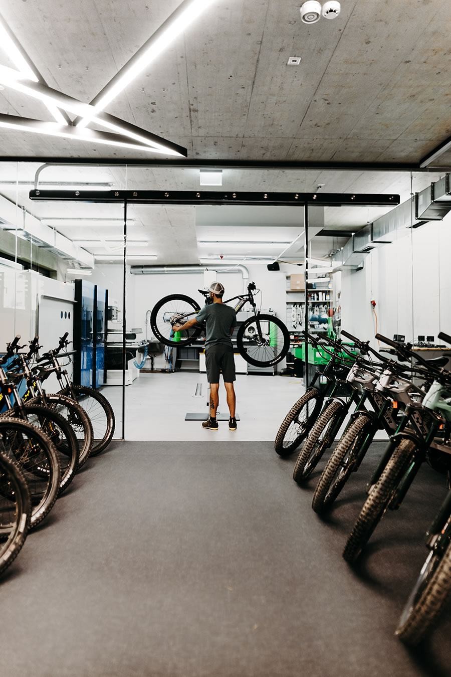 Mitarbeiter von Schernthaner sports mit Fahrrad, umgeben von weiteren Fahrrädern auf Ständern