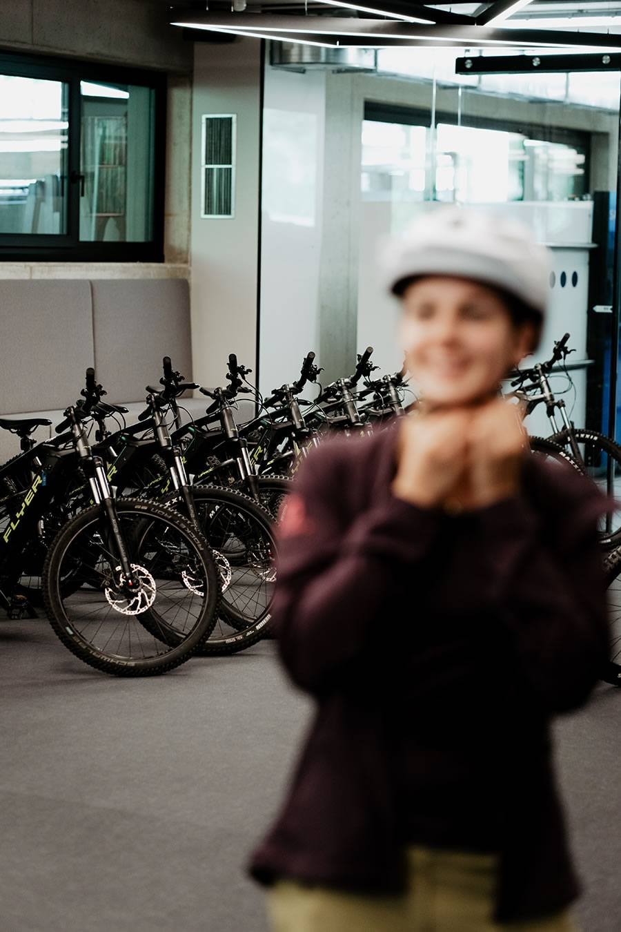 Verschwommenes Bild einer lächelnden Person mit Helm, Fahrräder im Hintergrund
