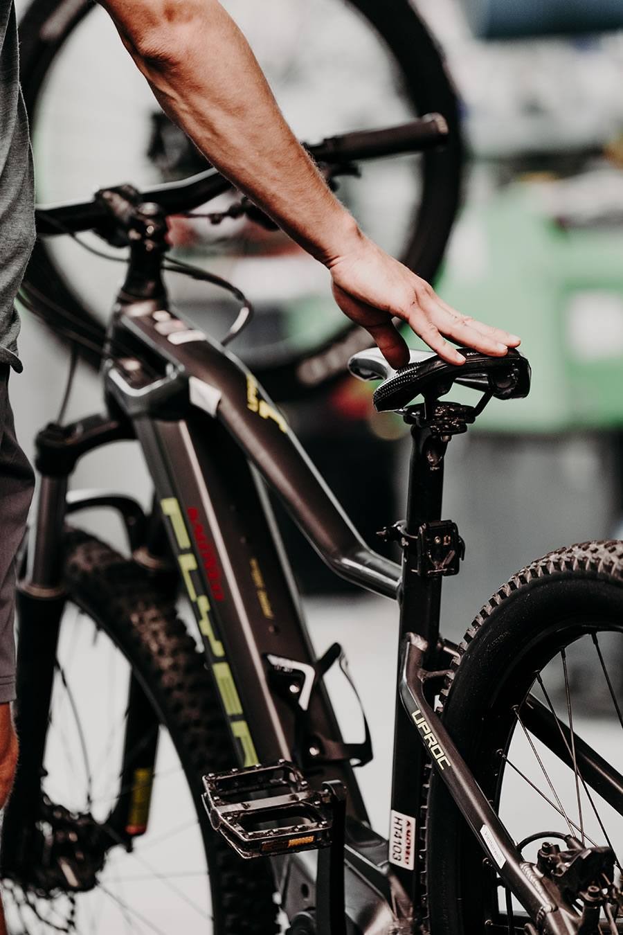 Ein Mitarbeiter von Schernthaner sports berührt den Sattel eines schwarzen E-Bikes
