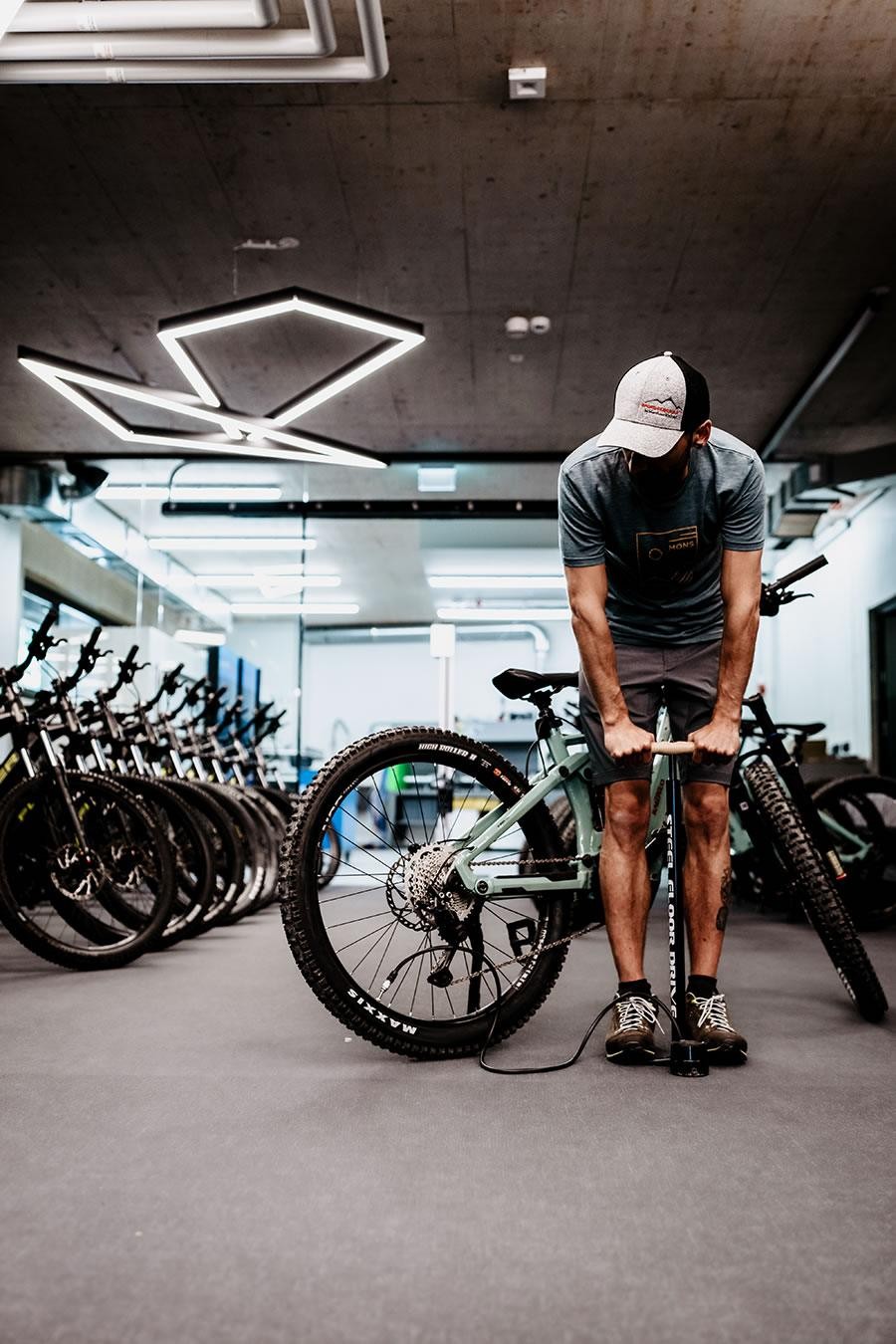 Mitarbeiter von Schernthaner sports pumpt einen Fahrradreifen in einem Raum voller Fahrräder auf