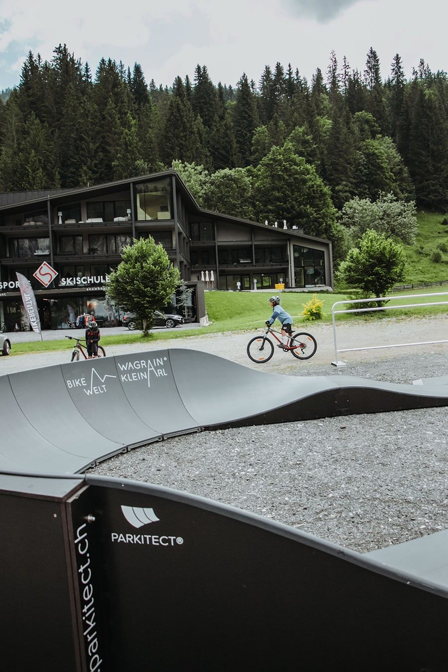 Kinder befahren den Pumptrackparcours vor Schernthaner sports in Kleinarl