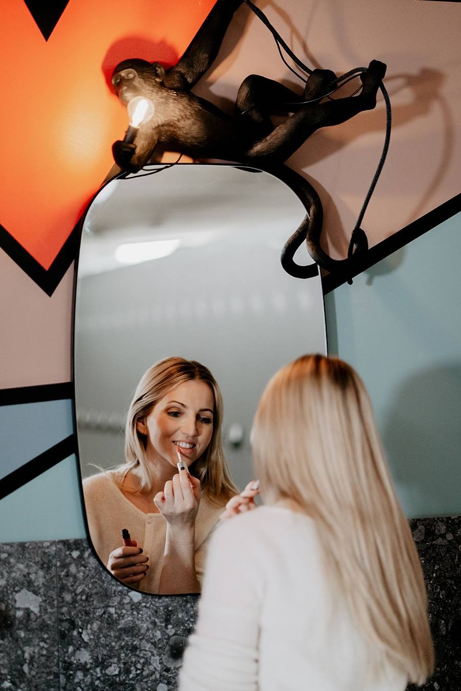 Eine Frau trägt vor einem Spiegel Lippenstift in der Beauty Station auf