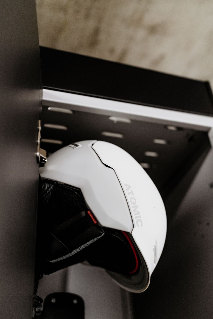 Weißer Helm im Spind an der Wand hängend im Skidepot