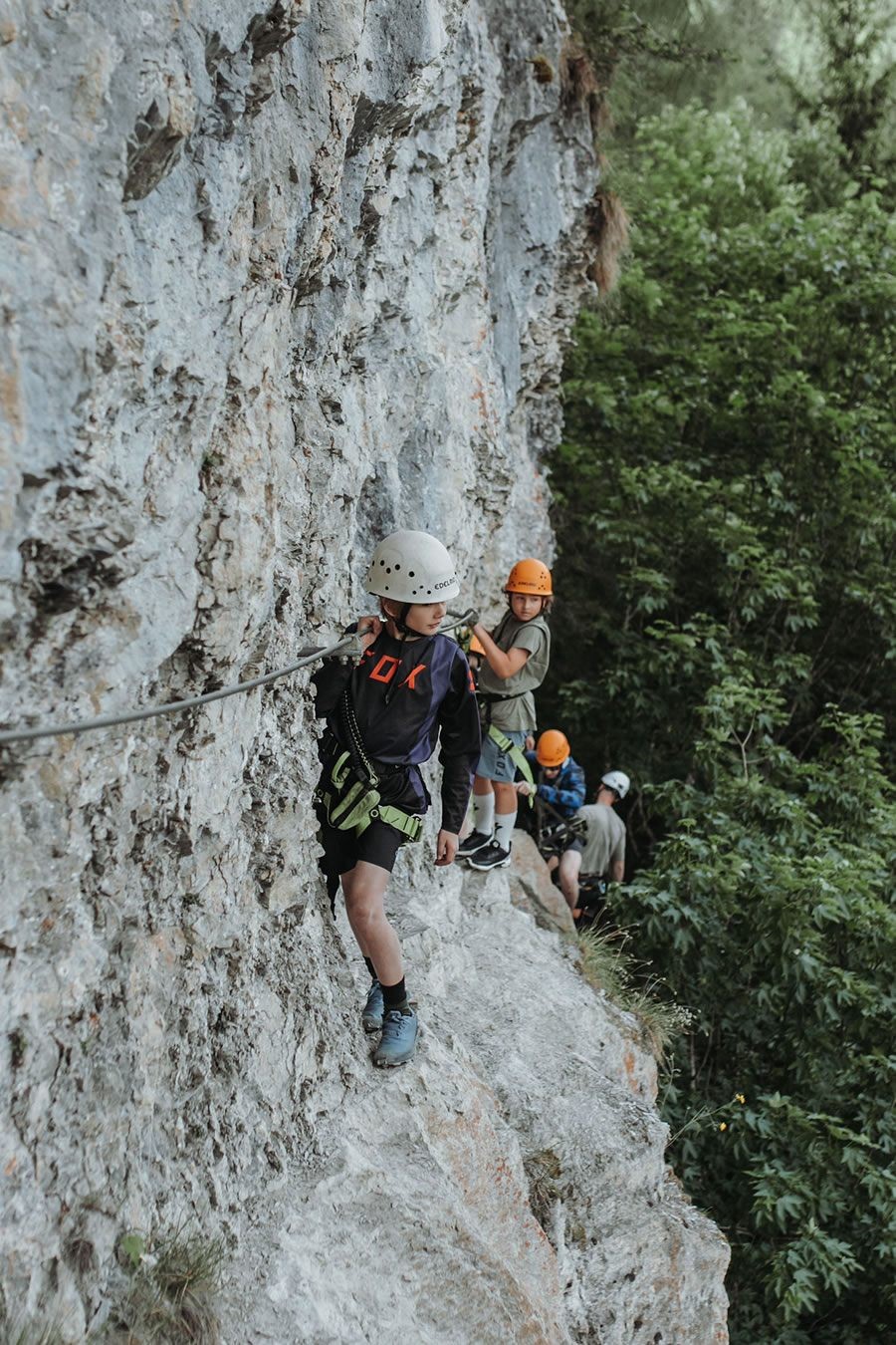 Kinder mit Kletterausrüstung an einer steilen Felswand im Klettersteig in Wagrain-Kleinarl