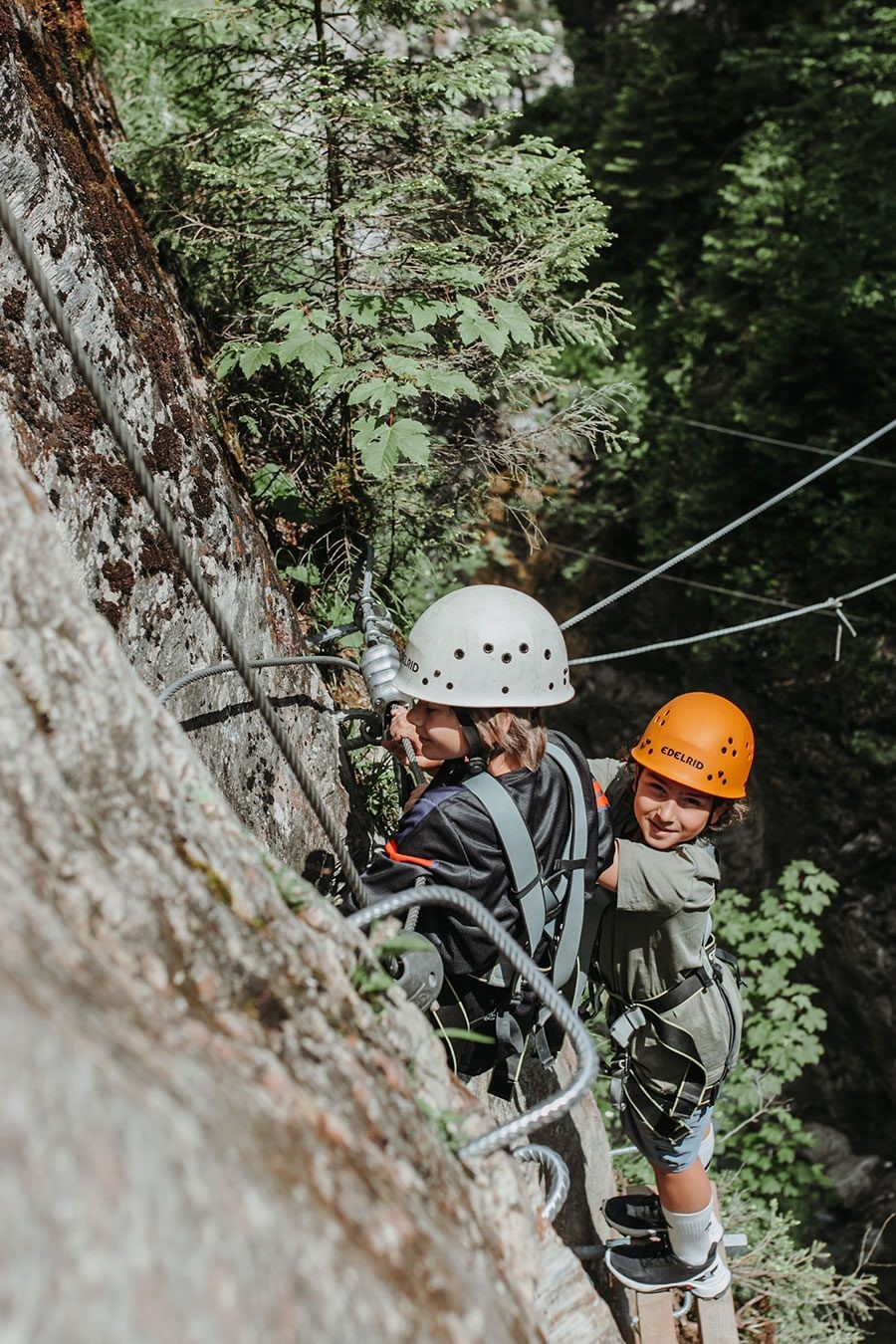 Zwei Personen klettern gesichert an einer Felswand mit Helmen und Kletterausrüstung auf dem Kletterstein in Wagrain-Kleinarl