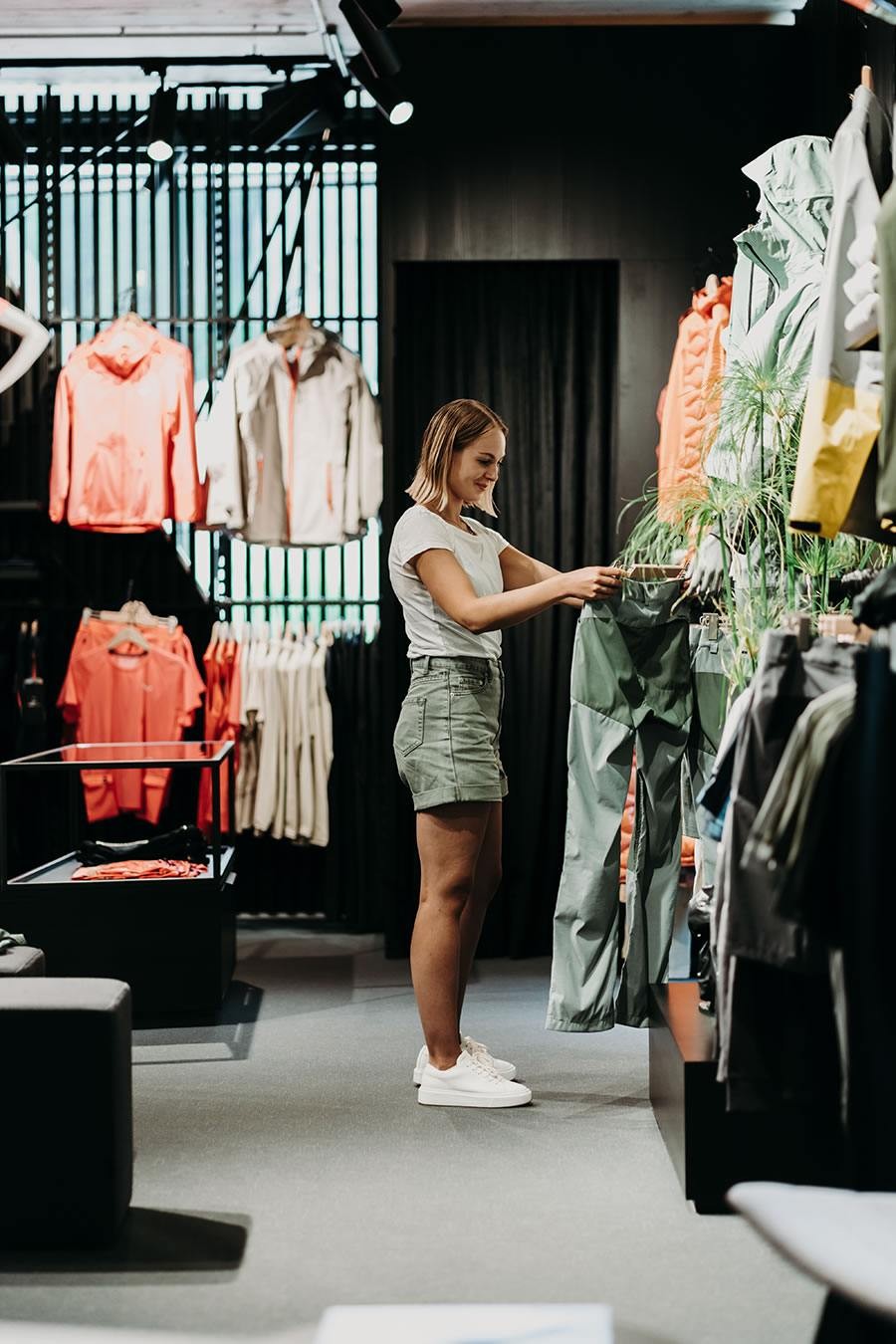 Eine Frau schaut sich in einem Bekleidungsgeschäft grüne Hosen an
