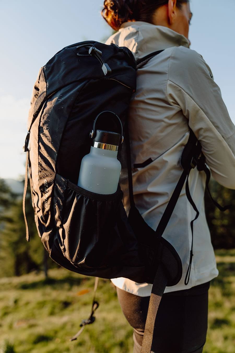 Eine Person mit Rucksack und Trinkflasche wandert in der Natur