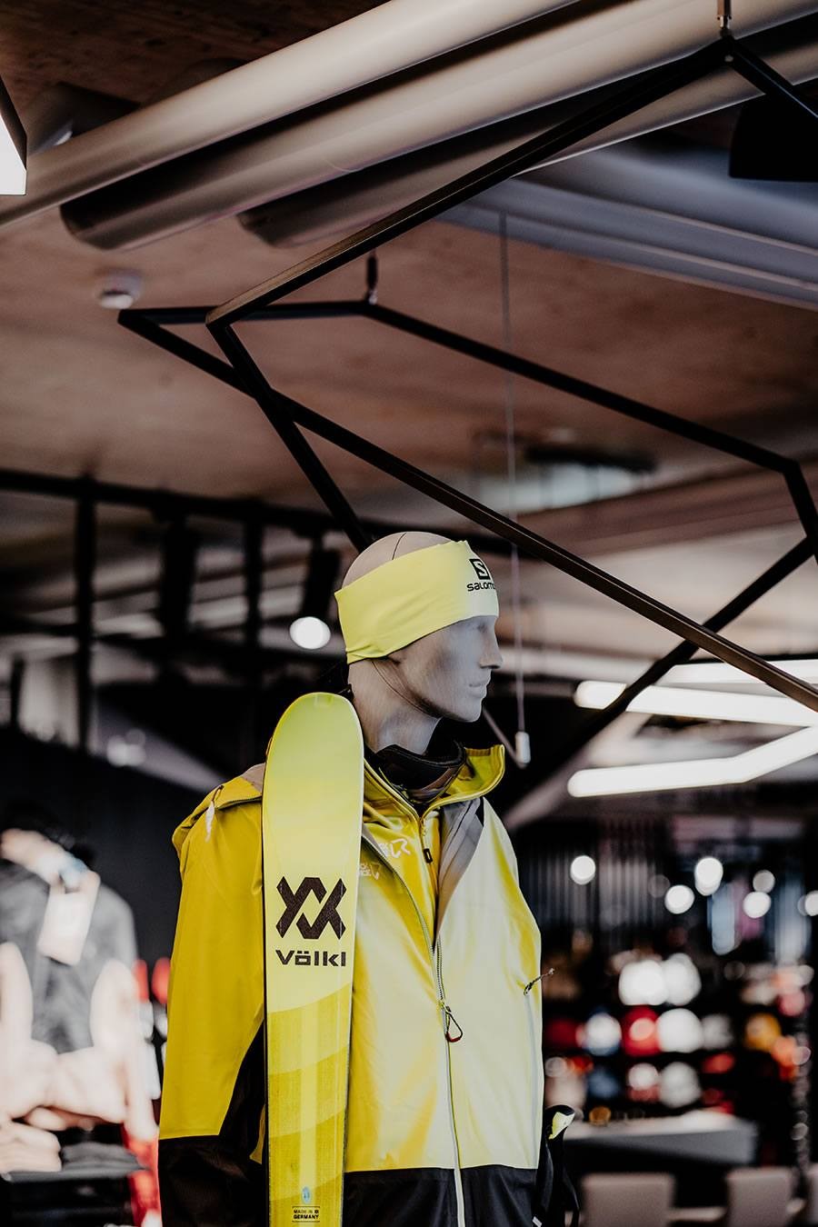 Schaufensterpuppe in gelber Jacke mit Ski-Ausrüstung in einem Sportgeschäft