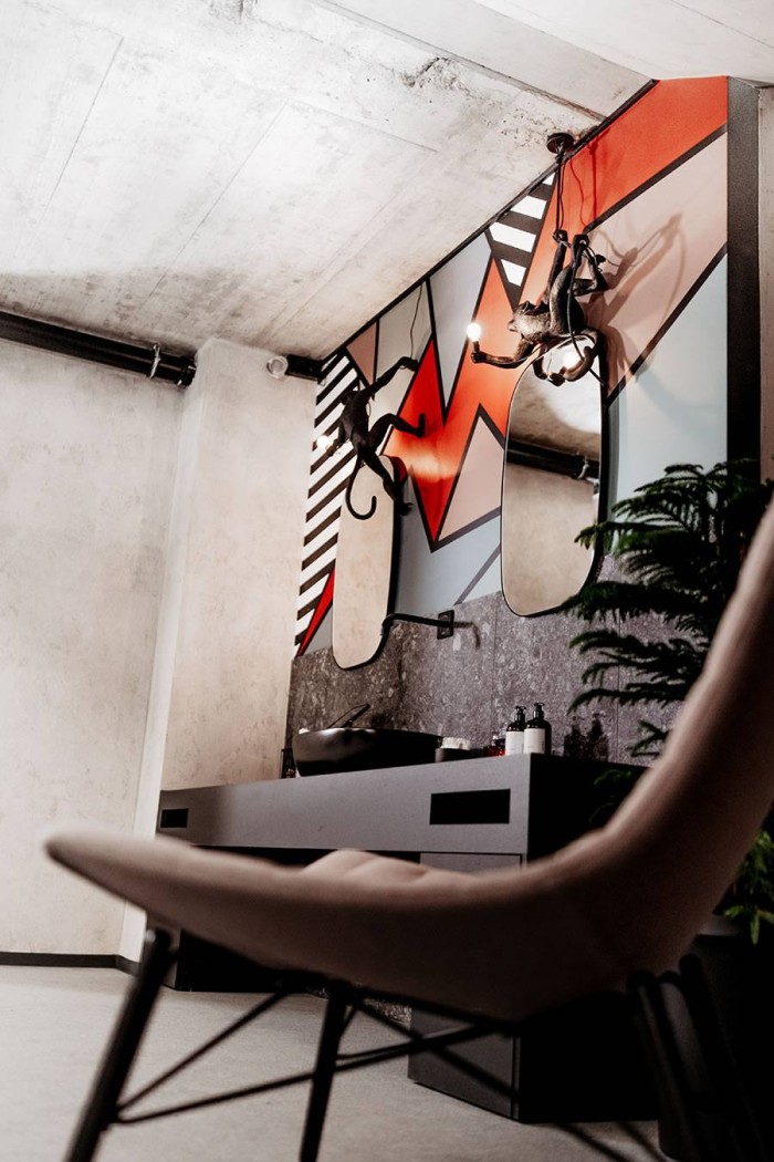 Modernes Bad mit bunter Wandkunst und verspielter Beleuchtung in Affenform