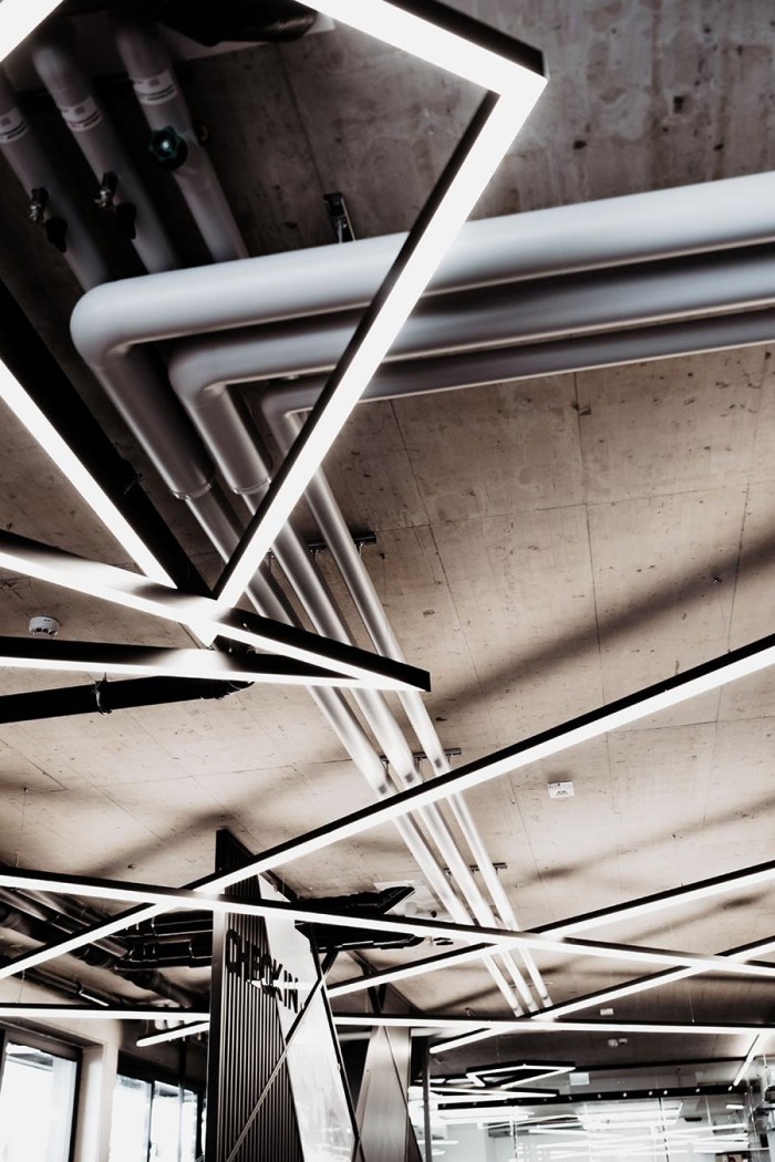 Geometrische LED-Leuchten zieren eine moderne Decke mit sichtbaren Rohren