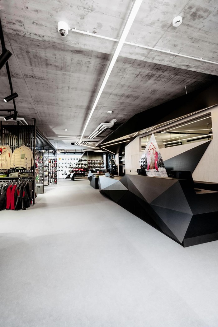 Moderner Ladeninnenraum mit geometrischem Tresen und ausgestellter Outdoorbekleidung