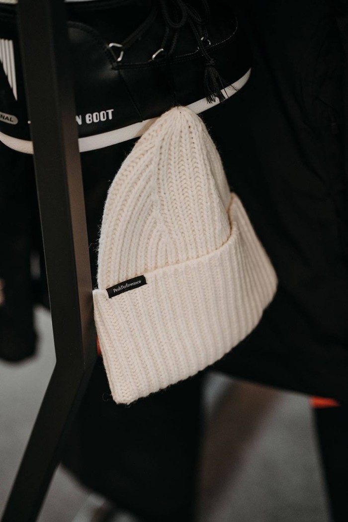 Weiße Strickmütze hängt neben einem schwarzen Schuh mit weißer Sohle