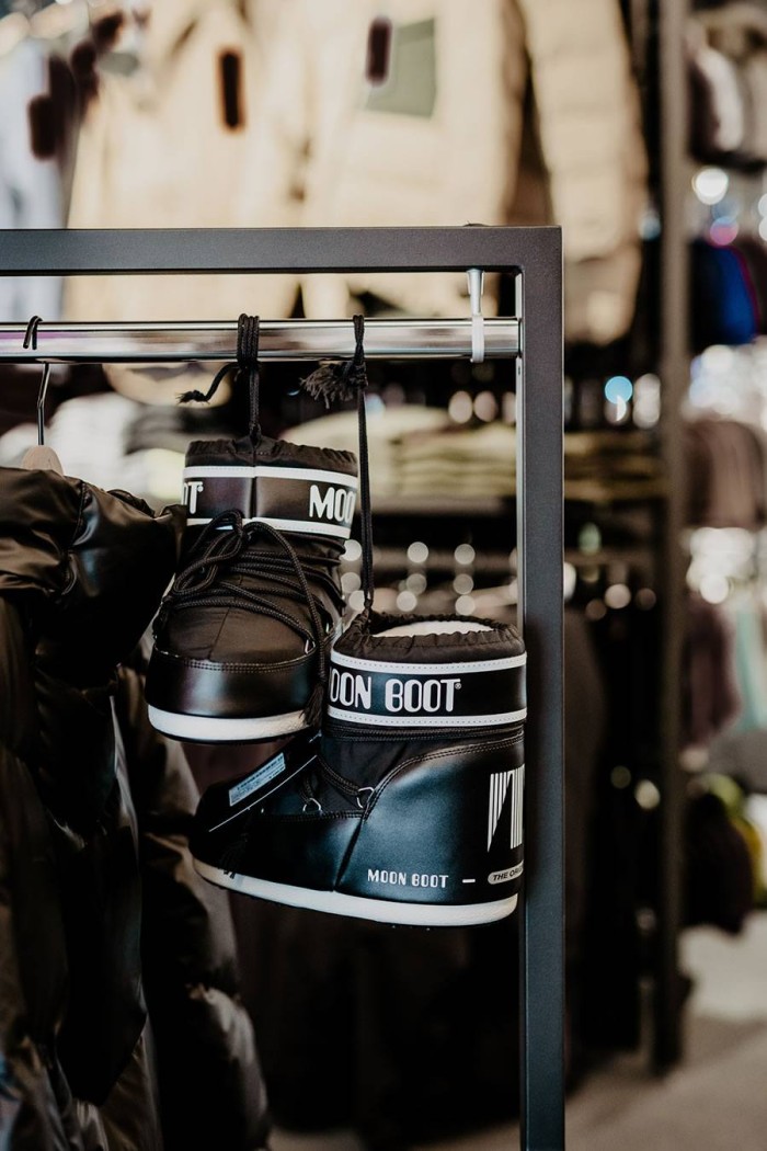 Schwarze Stiefel mit "Moon Boot"-Logo hängen in einem Bekleidungsgeschäft