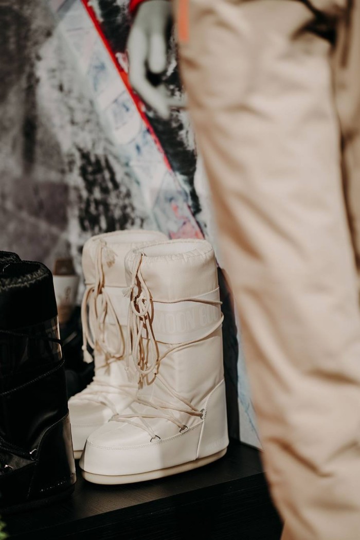 Weiße Moon Boots stehen auf einem Regal neben einem schwarzen Paar