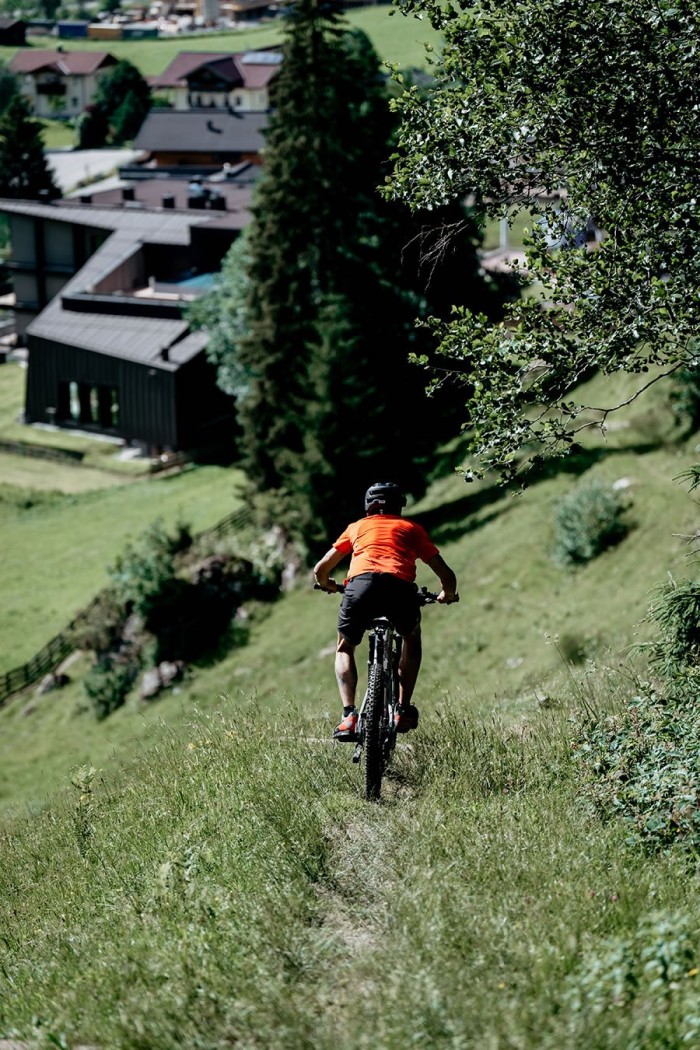 Eine Person fährt mit einem Fahrrad einen grasbewachsenen Hang hinunter