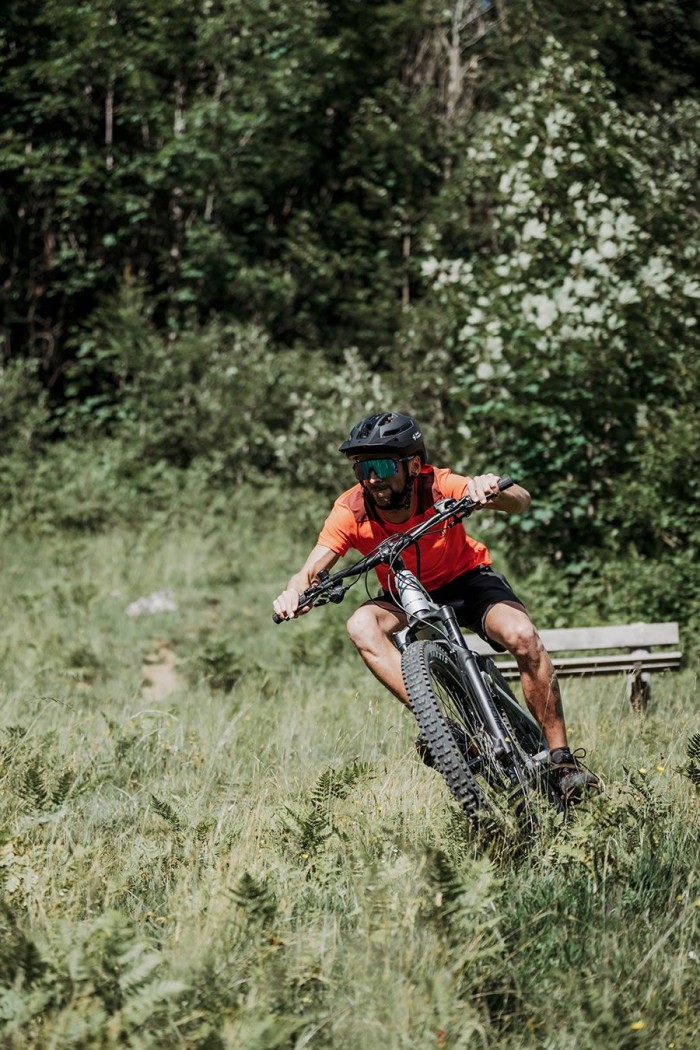 Eine Person fährt mit einem Mountainbike durch eine grüne, bewaldete Landschaft