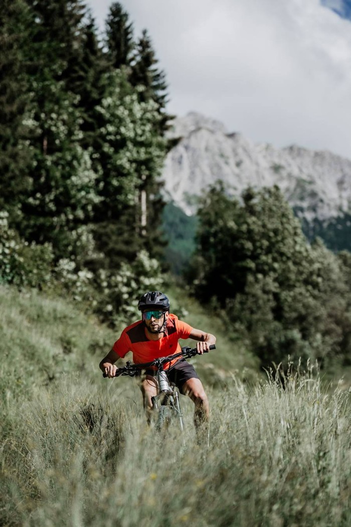 Ein Mountainbiker in rotem Trikot fährt durch eine bergige Waldlandschaft