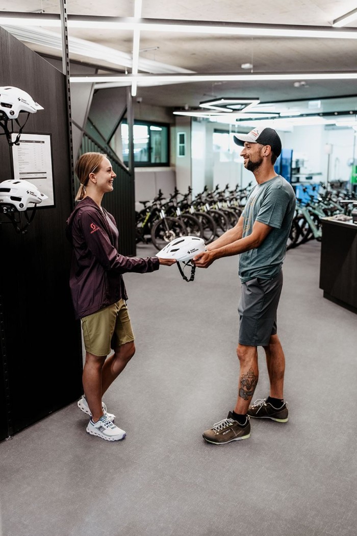 Eine Frau gibt einem Mann in einem Fahrradgeschäft einen Helm