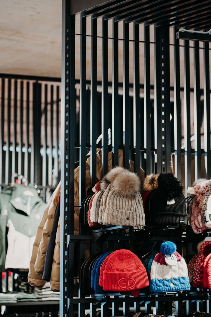 Verschiedene Wintermützen mit Pompons sind ordentlich auf einem Regal ausgestellt