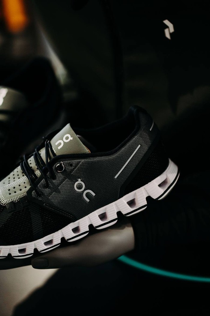 Grauer und schwarzer Sportschuh mit weißer Sohle auf einem dunklen Hintergrund