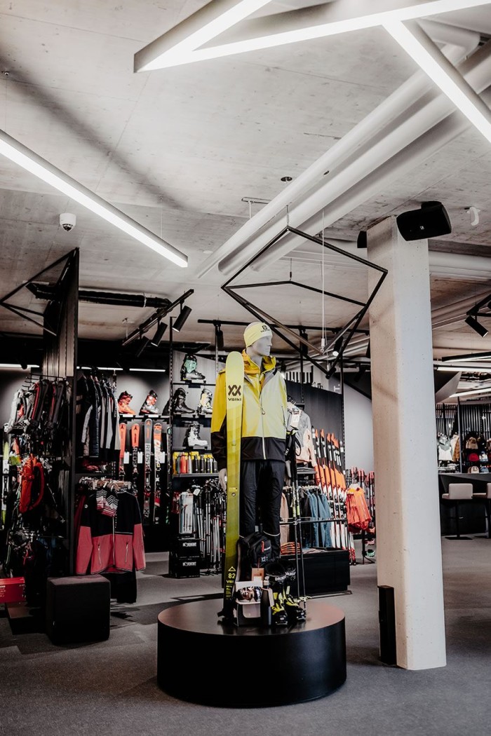 Schaufensterpuppe mit gelbem Skianzug und Ausrüstung in einem Sportgeschäft