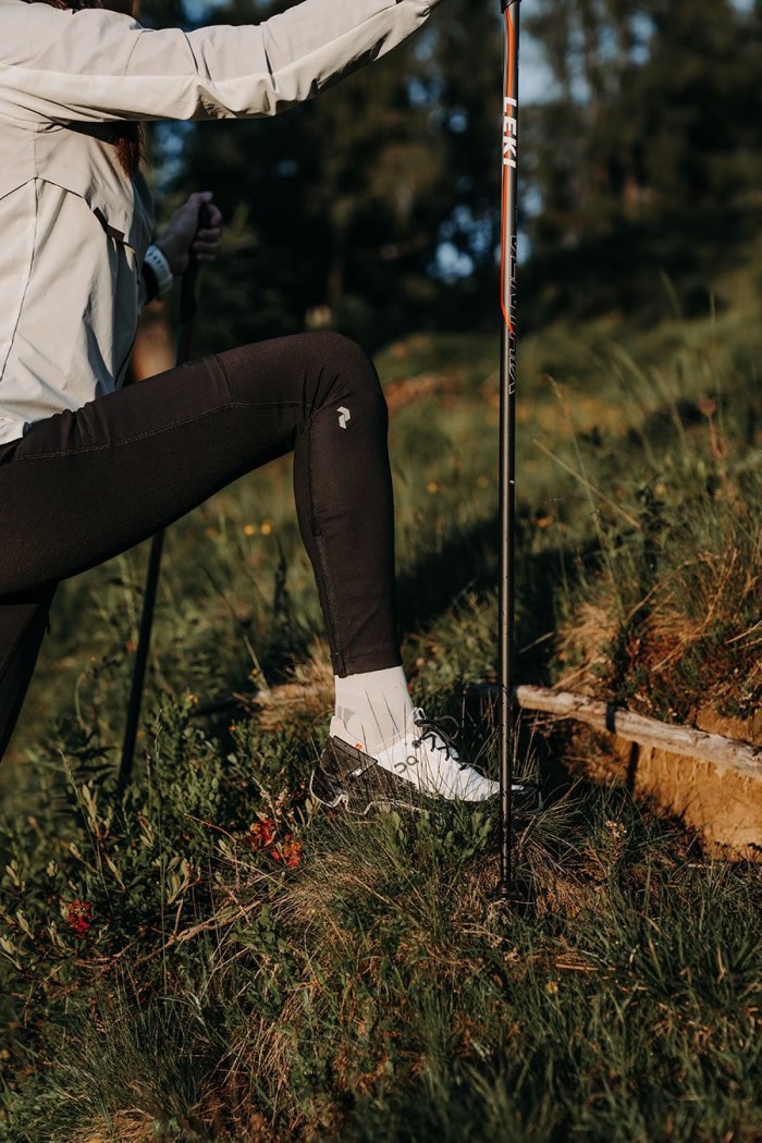 Person wandert mit Wanderstöcken in grasreicher Landschaft