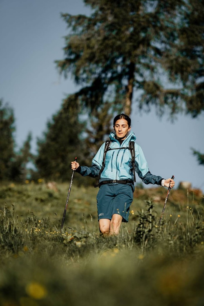 Frau wandert mit Trekkingstöcken in der Natur in sportlicher Kleidung