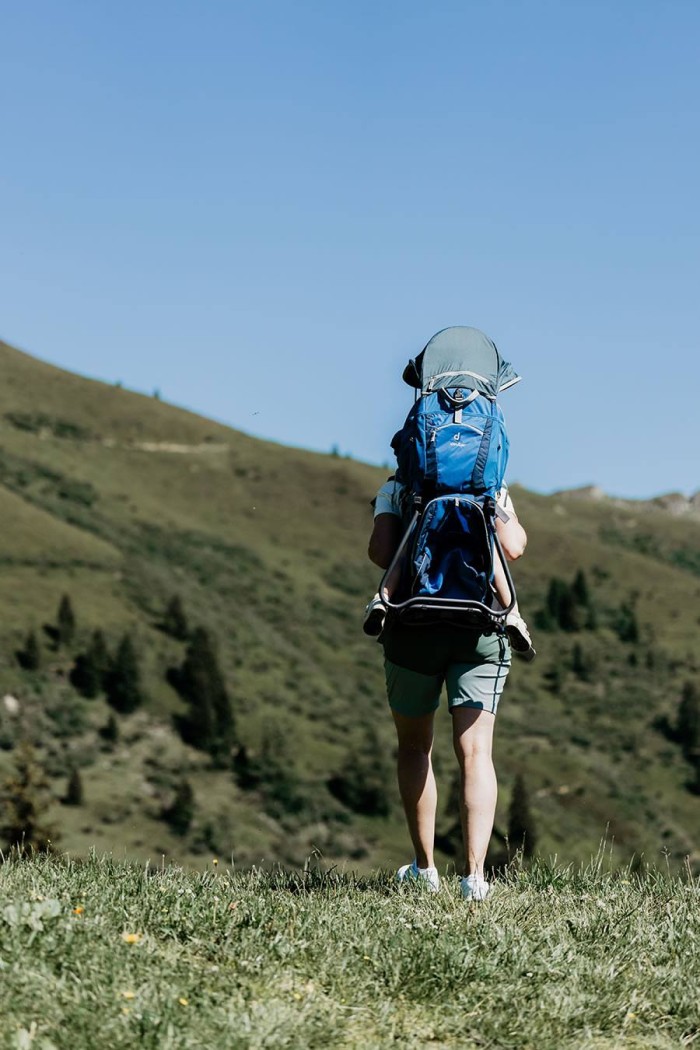 Eine Person wandert mit einem großen blauen Rucksack in einer bergigen Landschaft