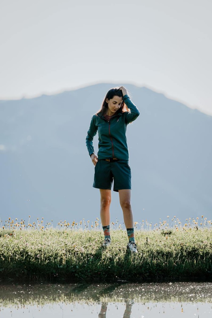Eine Person steht auf einer Wiese vor einem Berg im Hintergrund