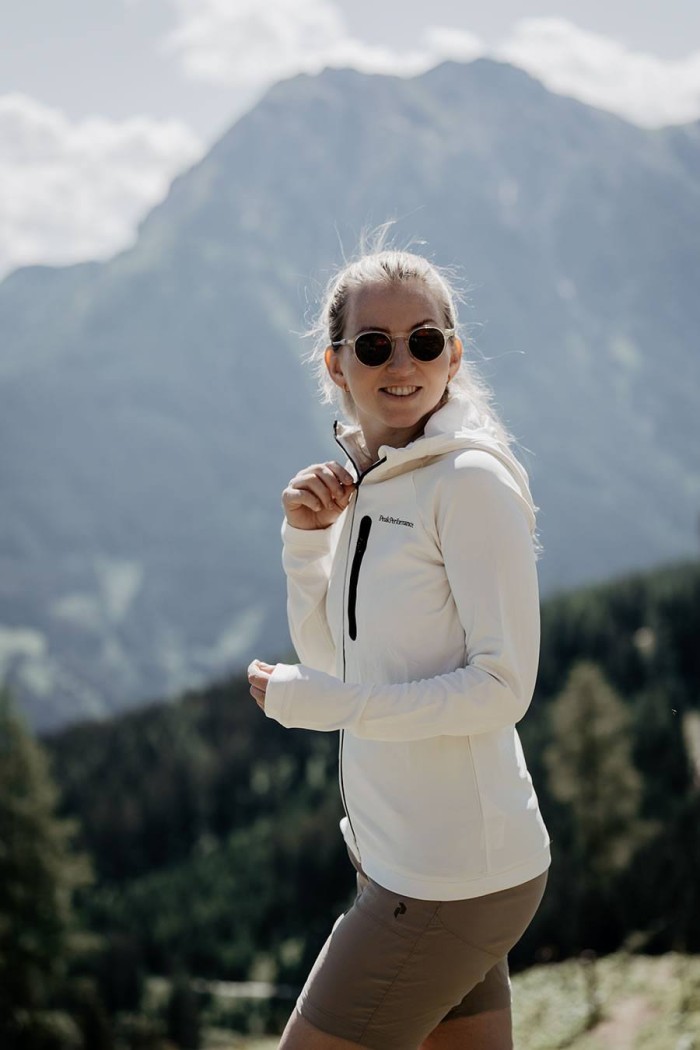 Eine Frau in Sportkleidung lächelt vor einer Berglandschaft