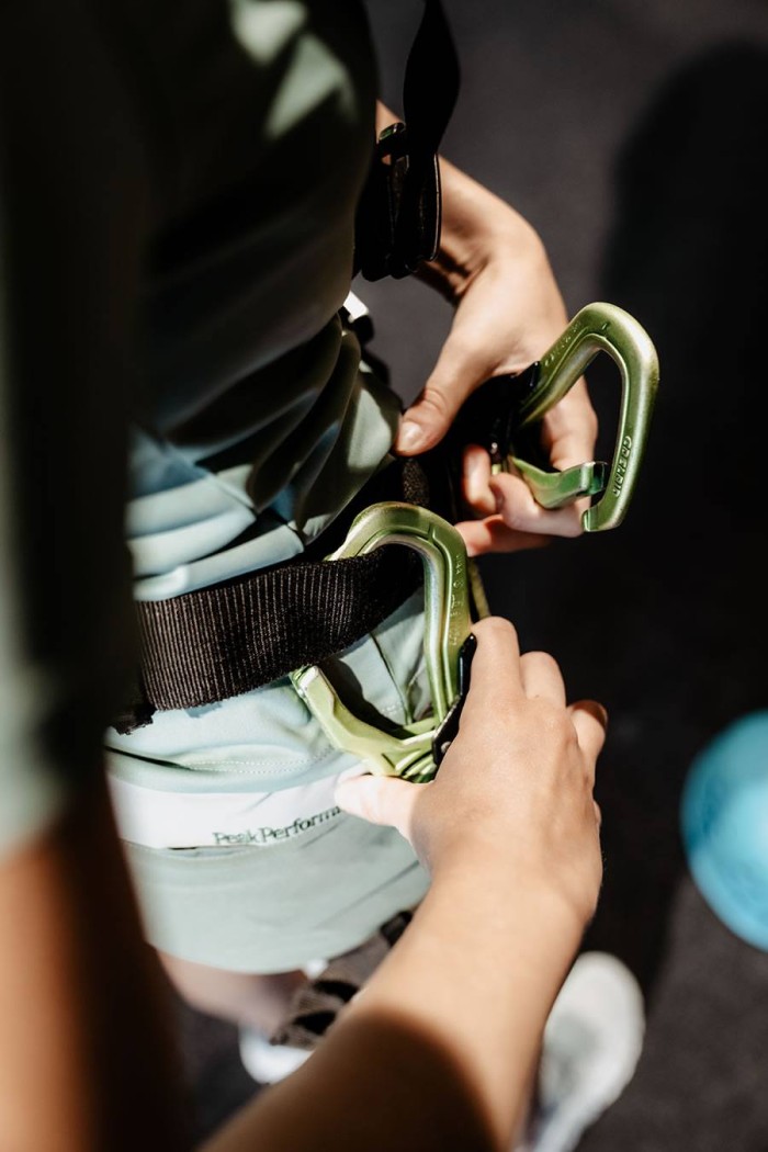 Eine Person befestigt Karabiner an einem Klettergurt