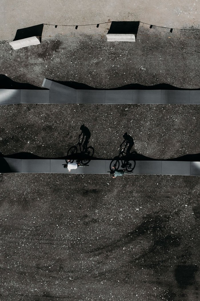 Zwei Fahrradfahrer fahren auf einem asphaltierten Weg mit sichtbaren Schatten