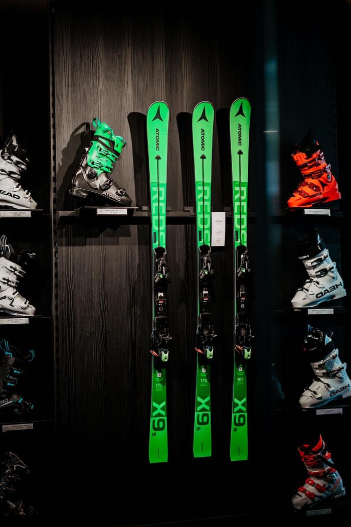 Grüne Skier und bunte Skischuhe sind im Regal ausgestellt