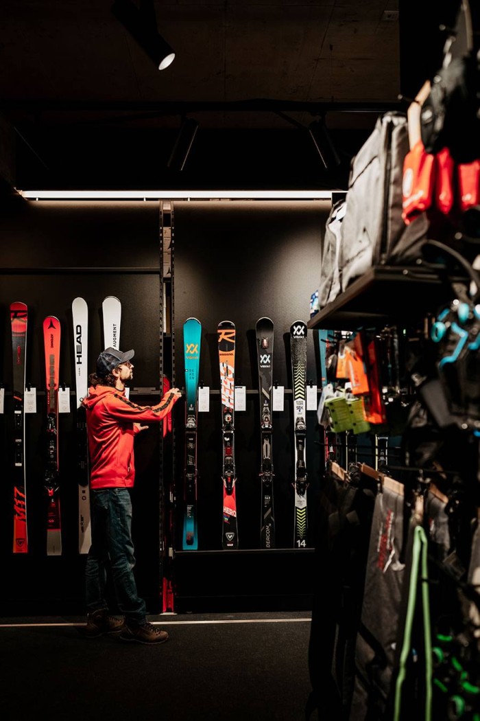 Ein Mann betrachtet Skier, die an einer Wand in einem Geschäft ausgestellt sind