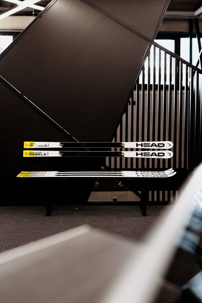 Ein Paar Skier liegt auf einer Bank vor einem modernen, dunklen Hintergrund