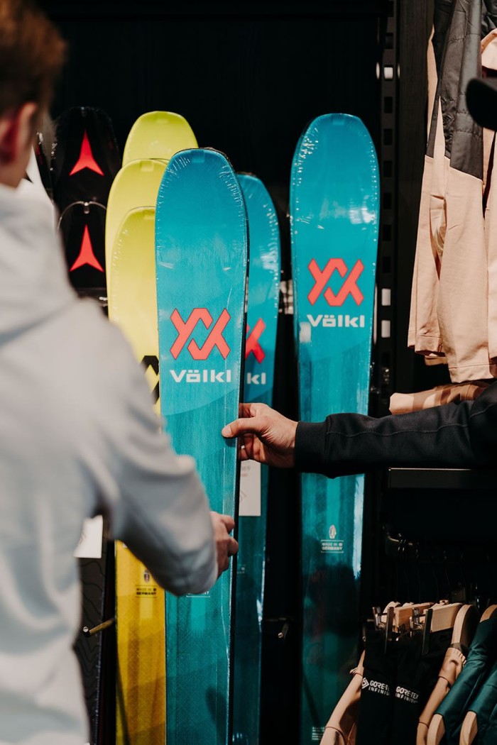 Zwei Personen betrachten bunte Skier in einem Sportgeschäft