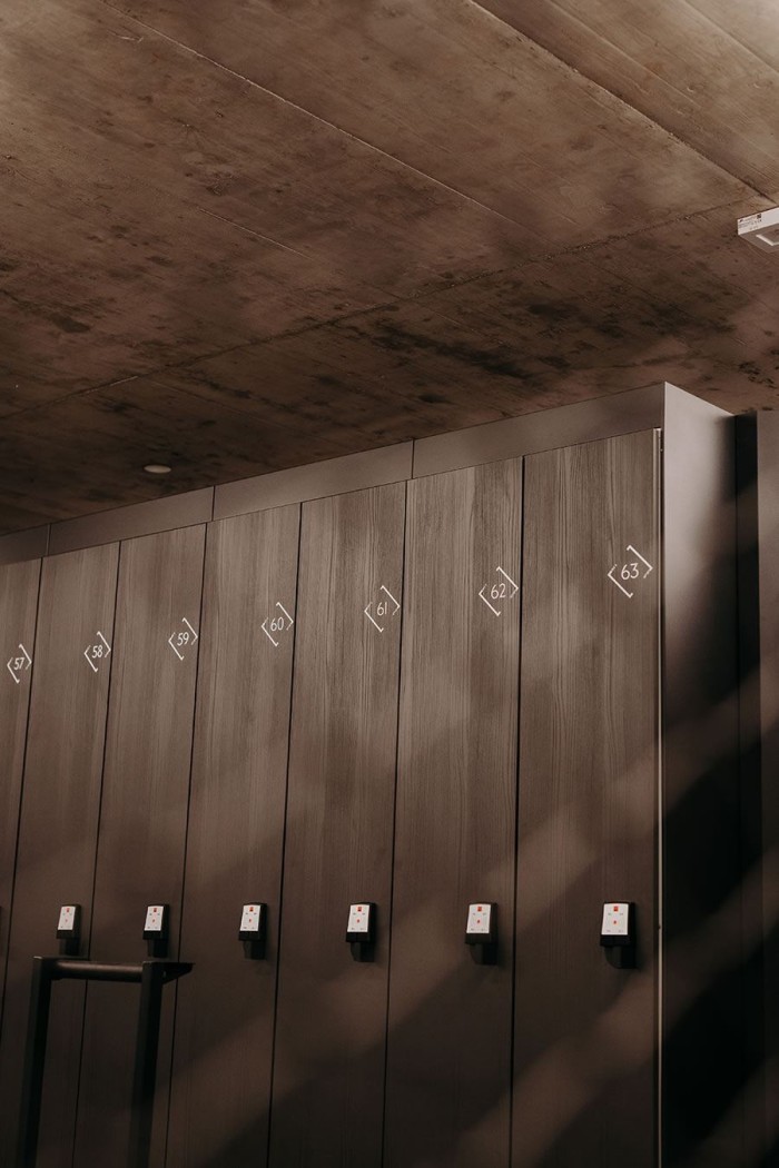 Holzschließfächer mit Nummern 57 bis 63 unter einer Betonwand