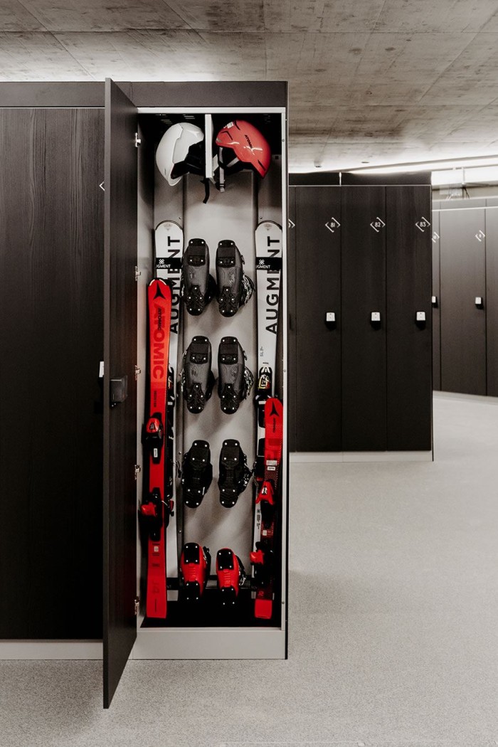 Offener Spind mit Ski, Helmen und Skischuhen in einem modernen Lagerraum