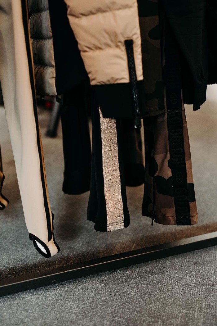 Verschiedene Kleidungsstücke hängen an einer Kleiderstange auf grauem Teppichboden