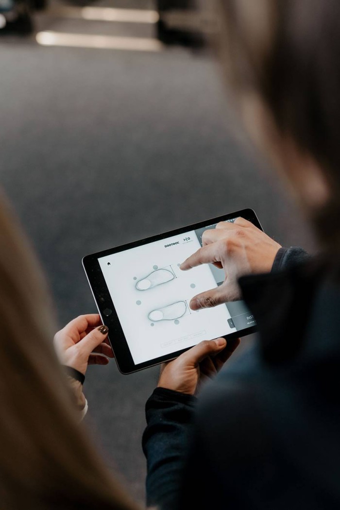 Zwei Personen betrachten ein Tablet mit grafischen Darstellungen von Schuhsohlen