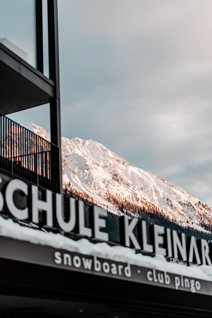 Skischule-Gebäude vor schneebedecktem Berg bei Sonnenuntergang