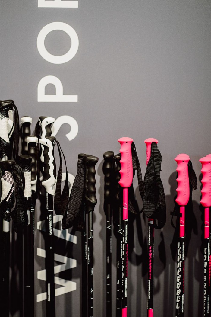 Mehrere Wanderstöcke mit schwarzen und pinken Griffen stehen vor einer grauen Wand