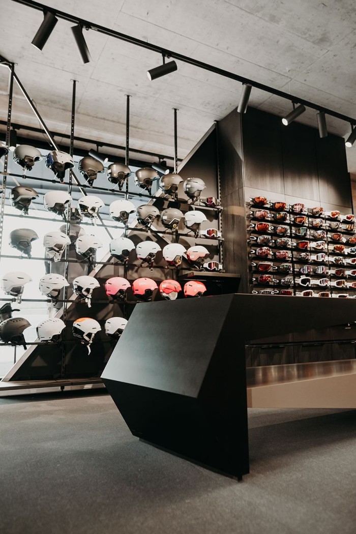 Wand mit zahlreichen Skihelmen und Brillen in einem modernen Geschäft