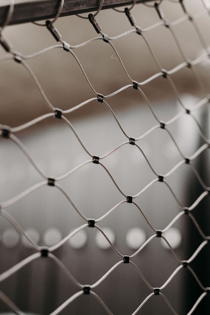 Drahtnetz mit schwarzen Knotenpunkten vor unscharfem Hintergrund