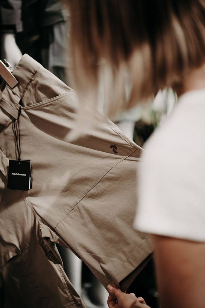 Person betrachtet eine beige Hose mit Etikett im Geschäft