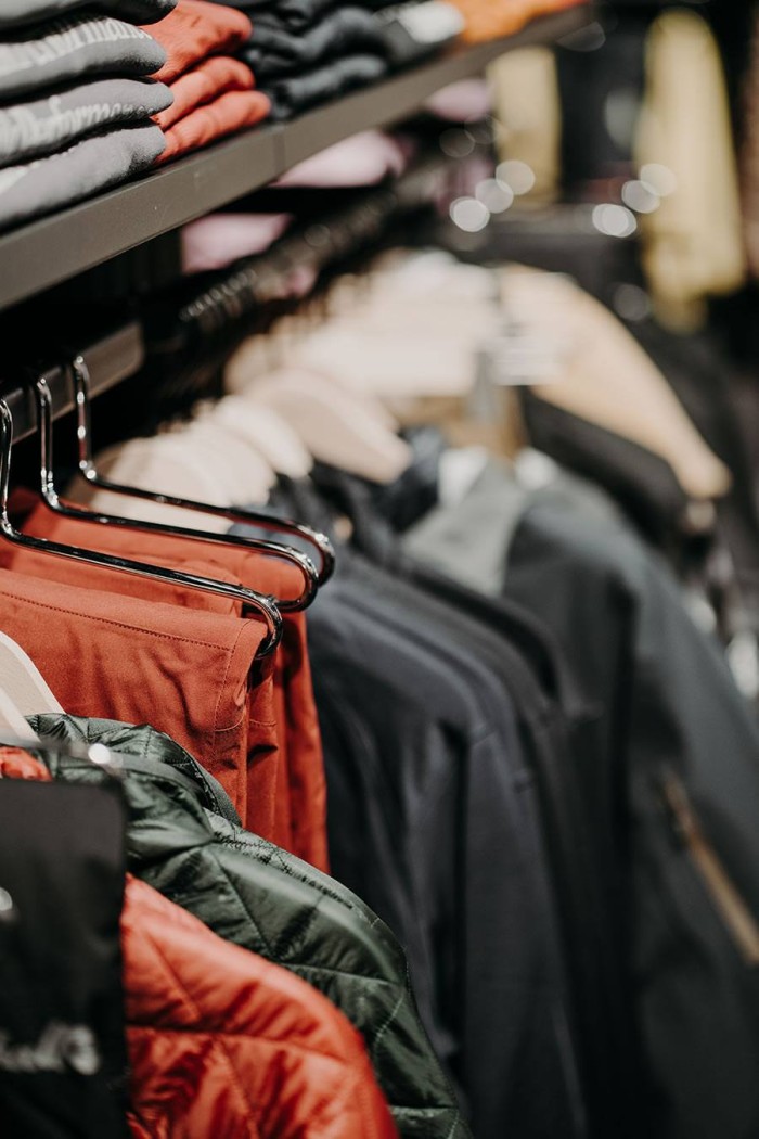 Jacken und Pullover hängen auf Kleiderbügeln in einem Laden