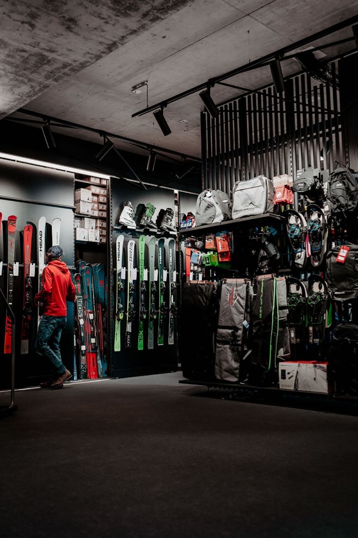 Ein Mann im roten Hoodie betrachtet Skiausrüstung in einem Sportgeschäft