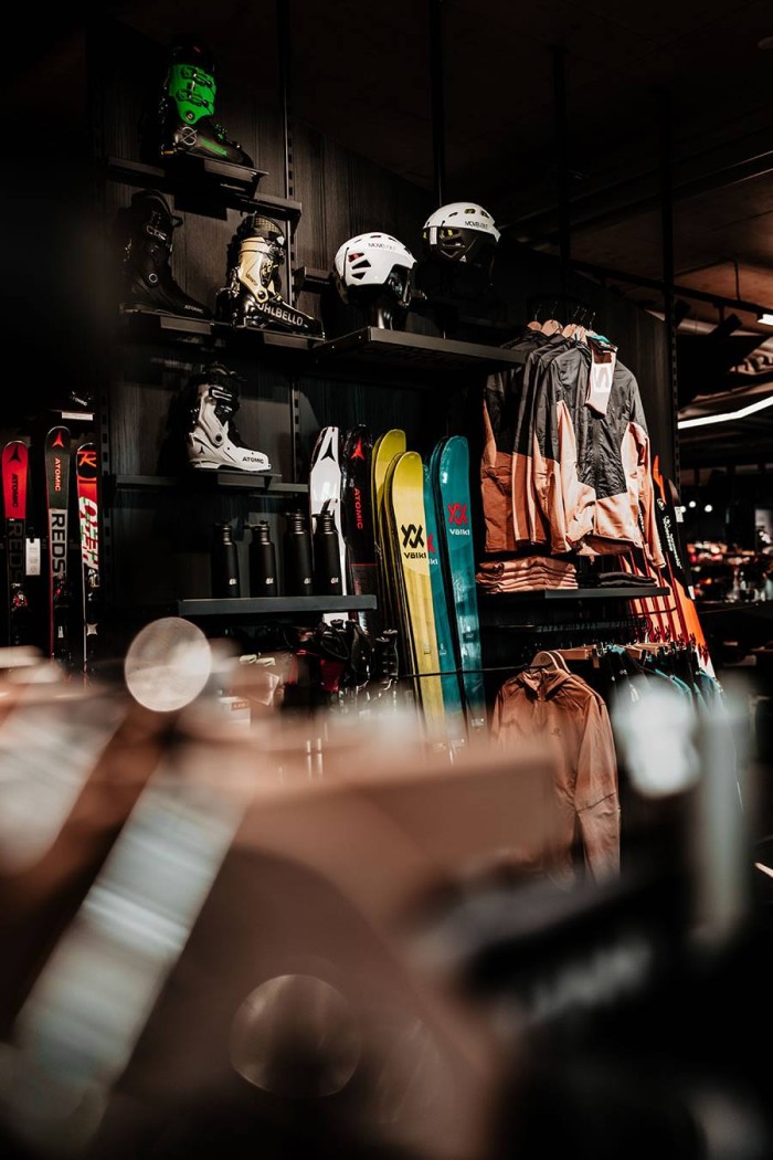 Regale in einem Sportgeschäft mit Ski, Helmen und Jacken