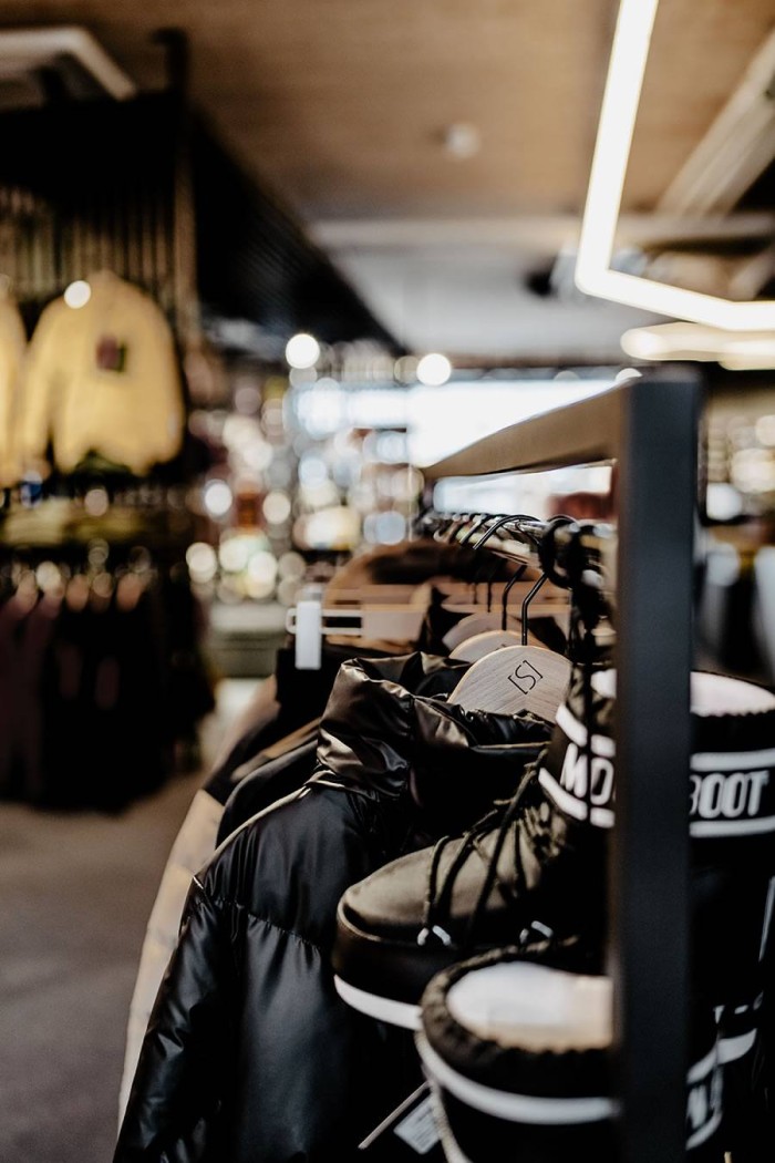 Kleidung und Stiefel auf Kleiderständer in einem Bekleidungsgeschäft