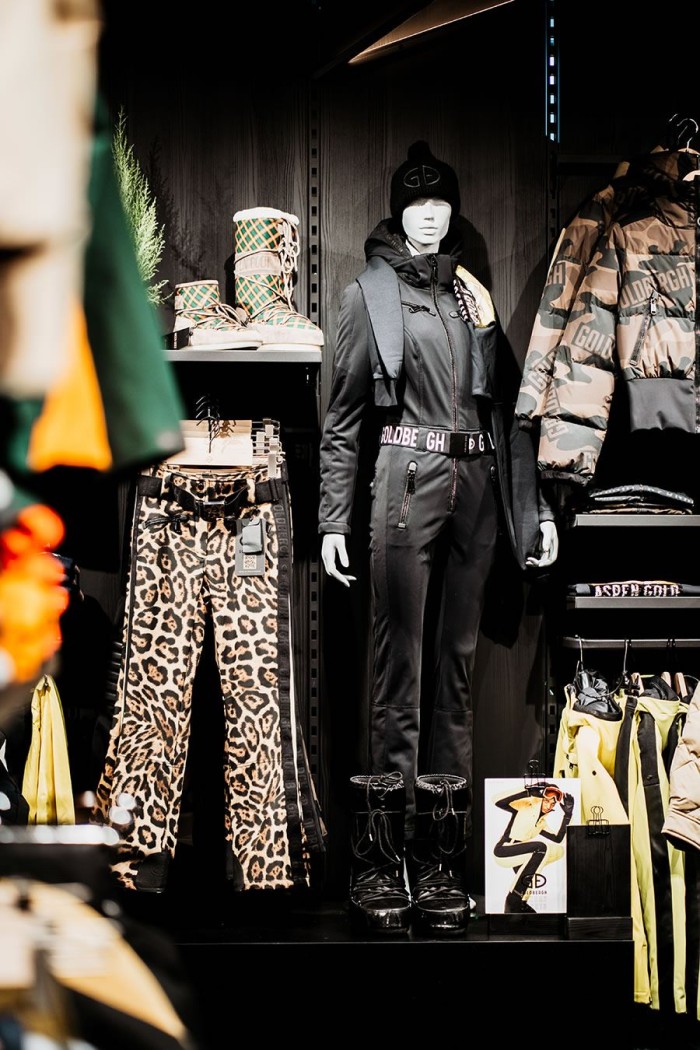 Schaufensterpuppe in schwarzer Sportkleidung, umgeben von Leopardenhosen und Jacken